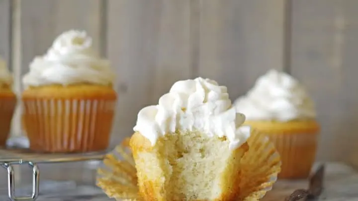 a gluten free vanilla bean cupcake with a bite out of it on a marble counter