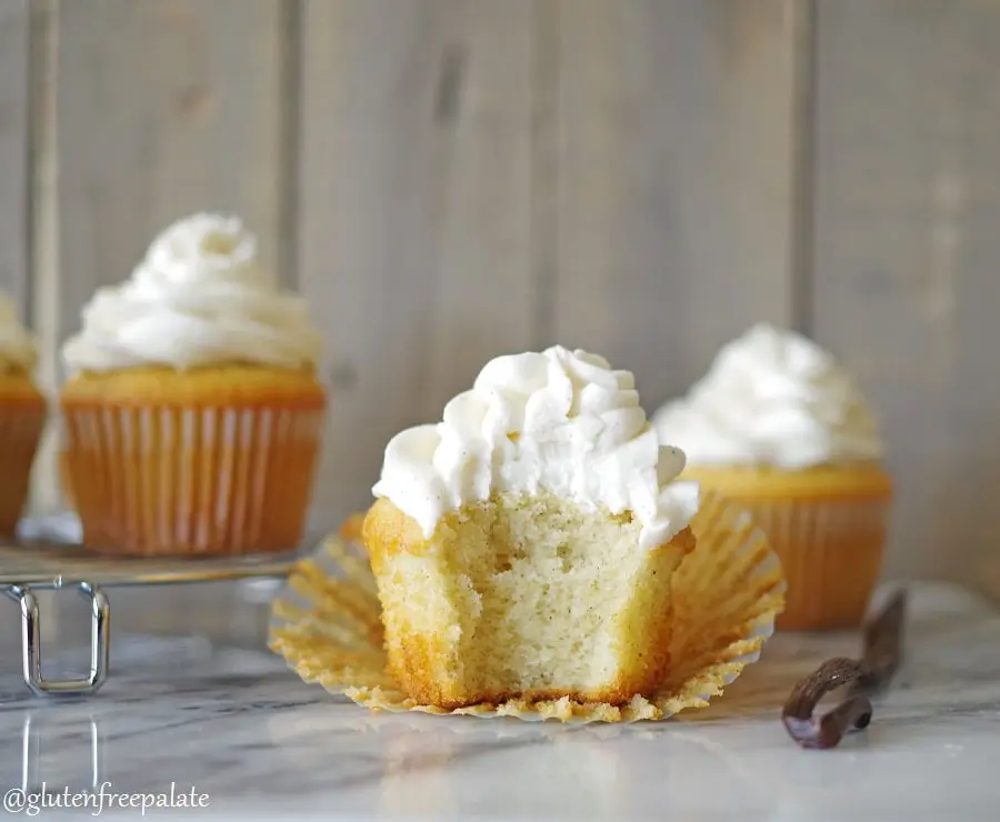 a gluten free vanilla cupcake topped with white frosting with a bite out