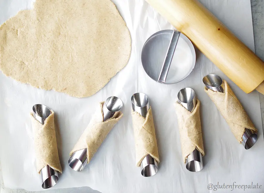 cannoli tubes wrapped with cannoli dough before frying in oil