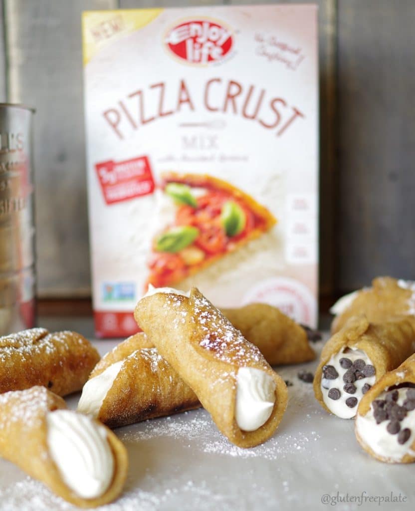 a side view of a top down view of cannolis dusted with powdered sugar in front of a pizza crust mix box