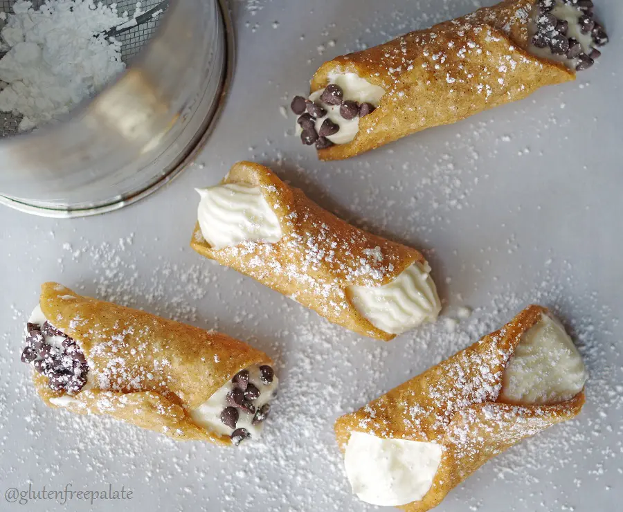 a top down view of four cannolis dusted with powdered sugar