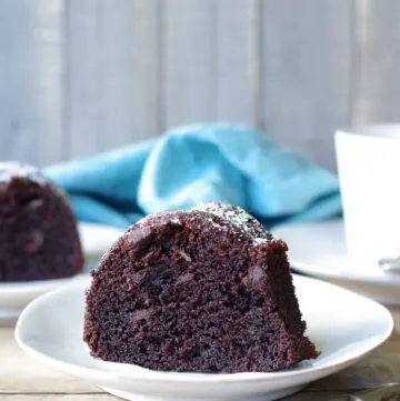 a slice of Gluten-Free Chocolate Bundt Cake on a white plate next to a fork