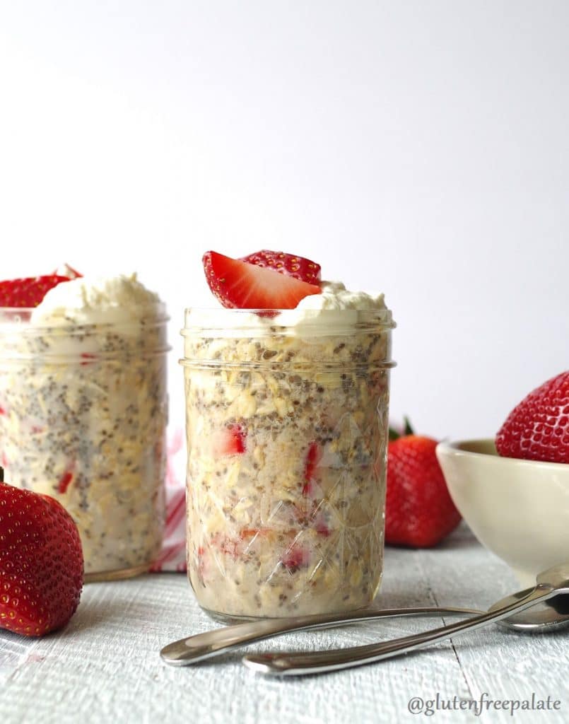 overnight oats with strawberries in a clear jar, topped with sliced strawberries
