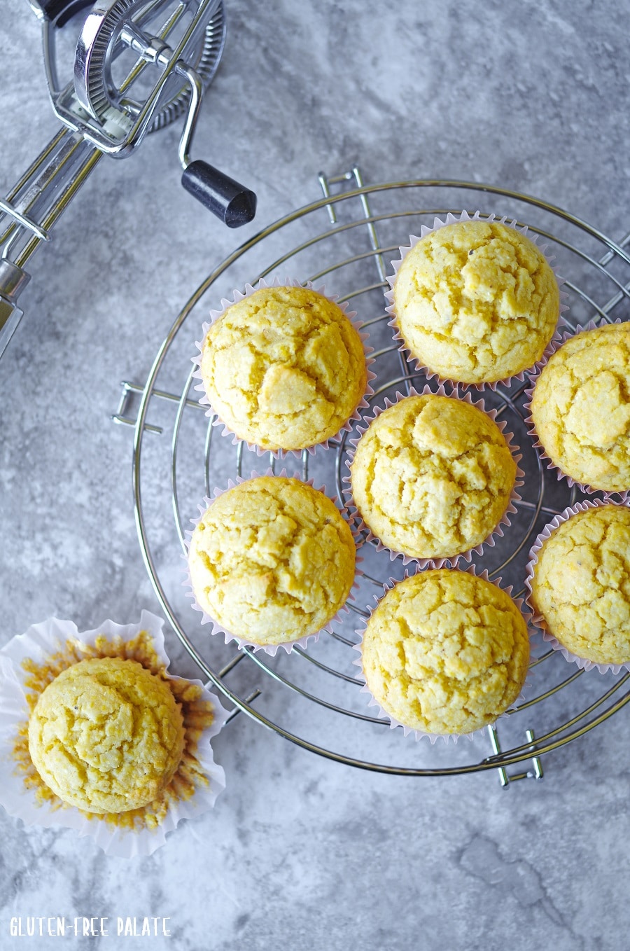 seven gluten-free cornbread muffins on a cooling rack next to a cornbread muffin on the counter