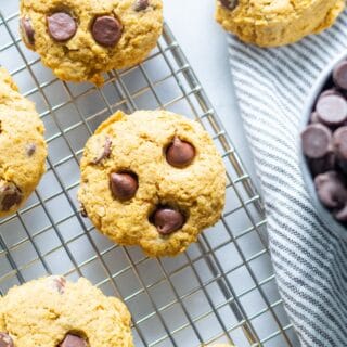 orange vegan pumpkin cookies with chocolate chips on a wire cooling rack