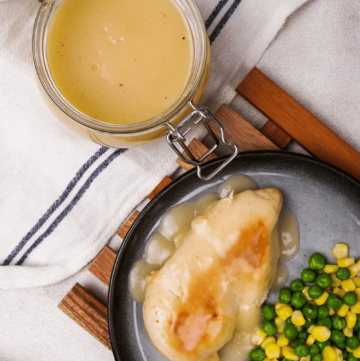 A glass jar of gluten-free gravy. A slice of turkey, covered in rich gravy, on a plate with peas and corn.