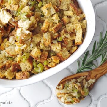 a close up of a wooden spoon serving gluten free stuffing out of a white dish