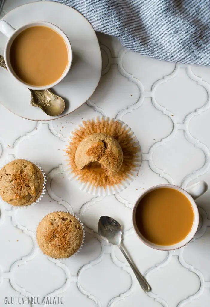 a top down view of paleo snickerdoodle muffins on a white counter next to two cups of coffee