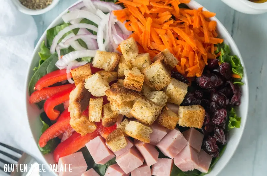 close up of a salad topped with gluten-free croutons and veggies and ham