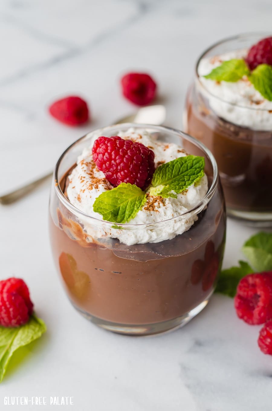 a close up of Gluten-Free Chocolate Pudding in a jar topped with whipped cream a raspberry