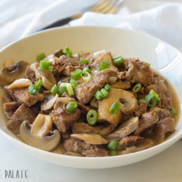 a side view of beef tips and mushrroms on a white plate
