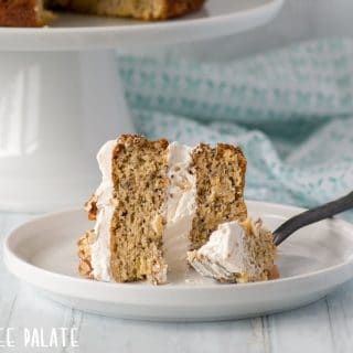 a close up of a slice of gluten free hummingbird cake on a white plate with a fork