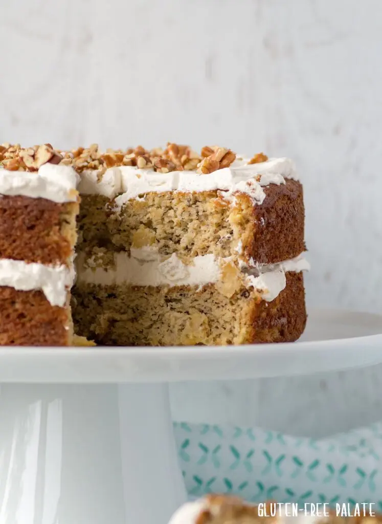 Grain-Free Hummingbird Cake with a slice taken out on a white cake stand