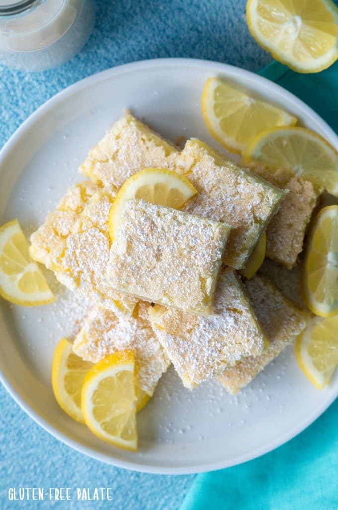 a top down view of lemon bars stacked on a white plate