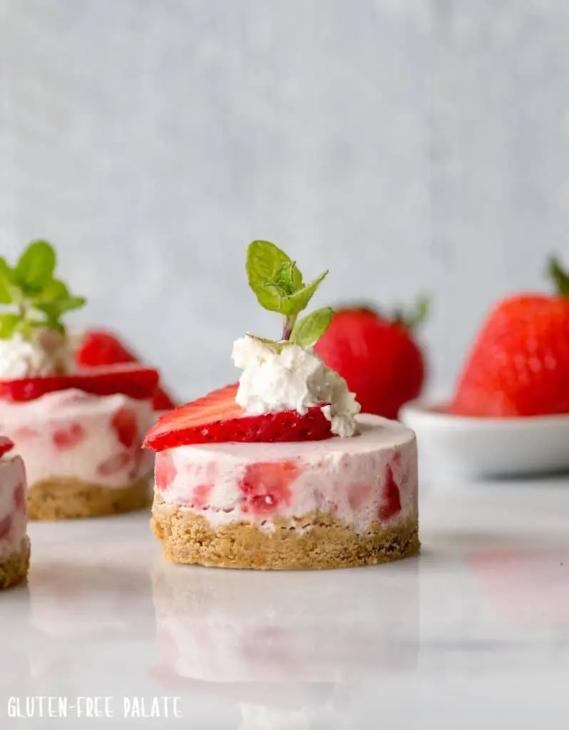 mini strawberry cheesecakes with whipped cream and a mint leaf on top
