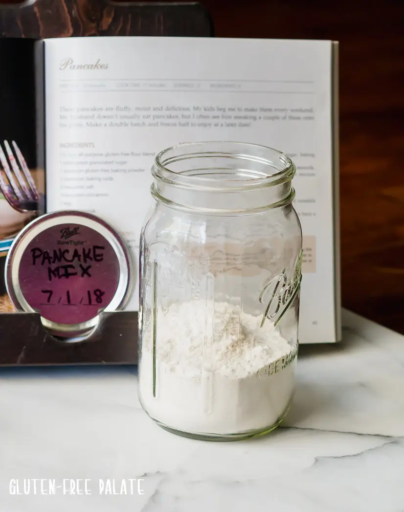a jar with dry gluten-free pancake mix in front of a cookbook