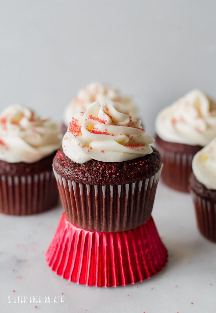 Gluten-Free Red Velvet Cupcakes topped with white frosting and red sprinkles.