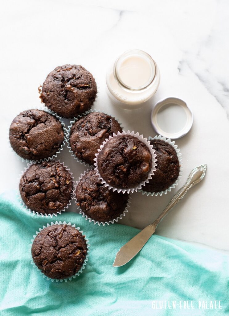 top view of Chocolate Zucchini Muffins with a blue kitchen towl and a jar of milk