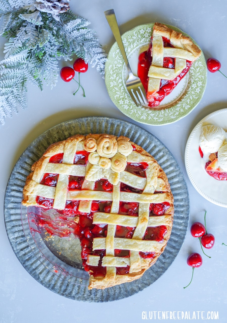 Gluten-free Cherry Pie on a tin plate next to two plates of slices of cherry pie