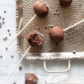 a close up of Gluten-Free Cake Pops covered in chocolate on a stick, on a metal tray