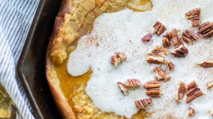 a close up of Gluten free pumpkin spice dutch baby in a cast iron skillet topped with chopped pecans