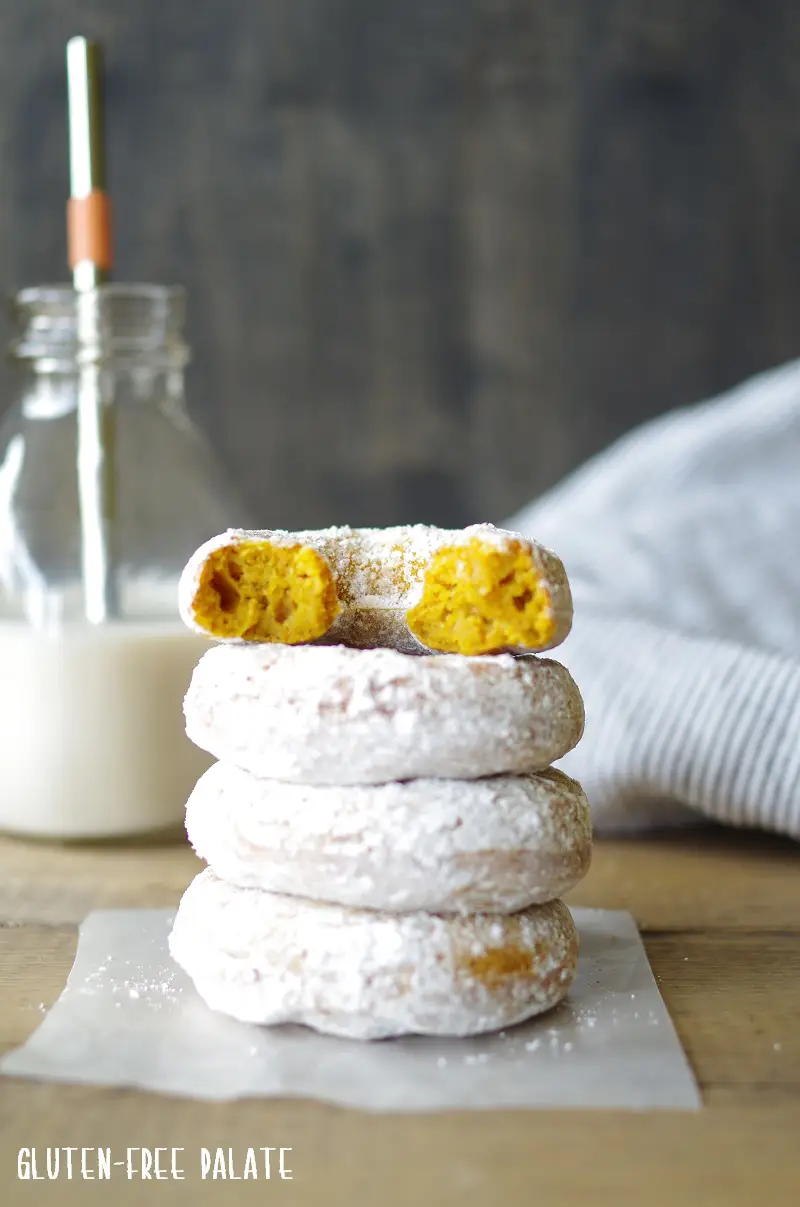 four gluten-free pumpkin donuts stacked one with a bit out