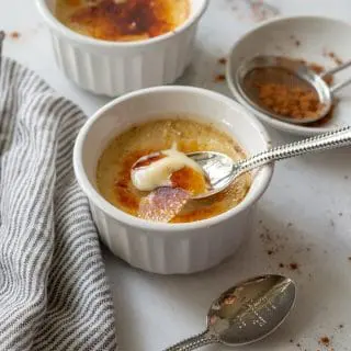 a close up of Chai Crème Brulée in a white ramekin with a spoon taking a bite out
