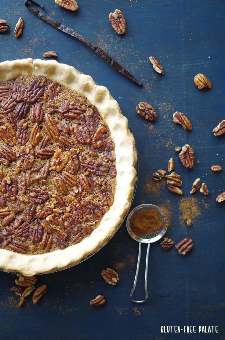 close up of gluten-free pecan pie on blue wood topped with cinnamon