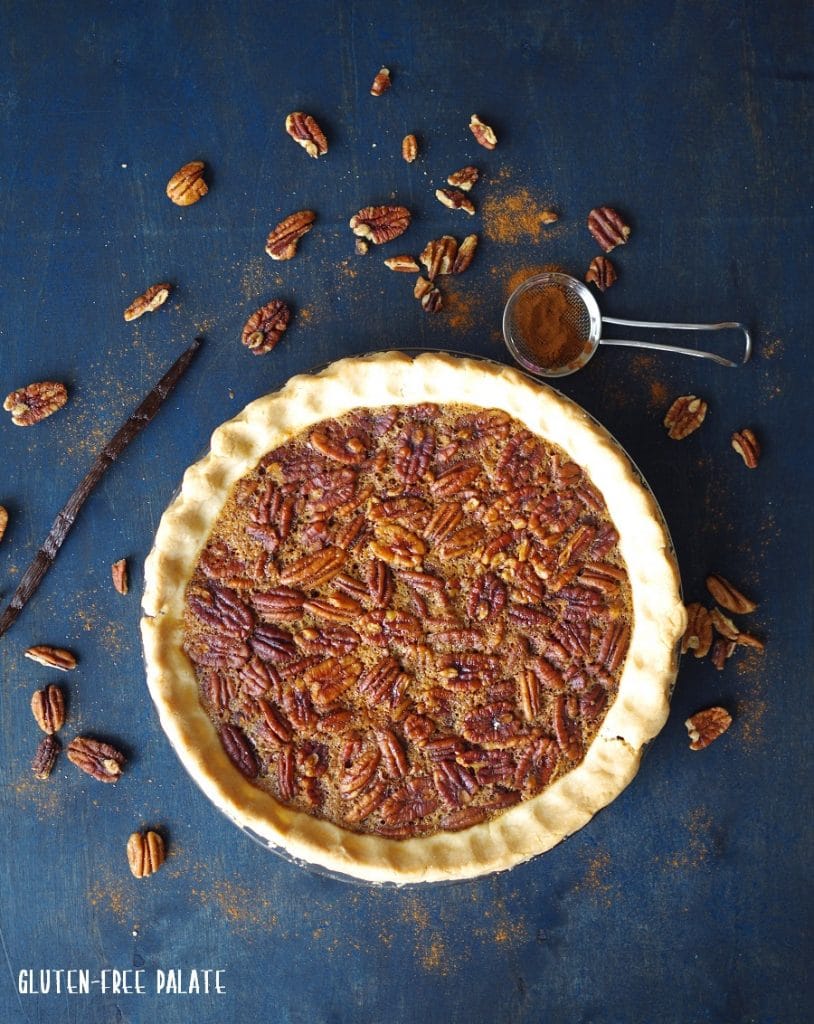 a paleo pecan pie in a pie plate with scattered pecans around it