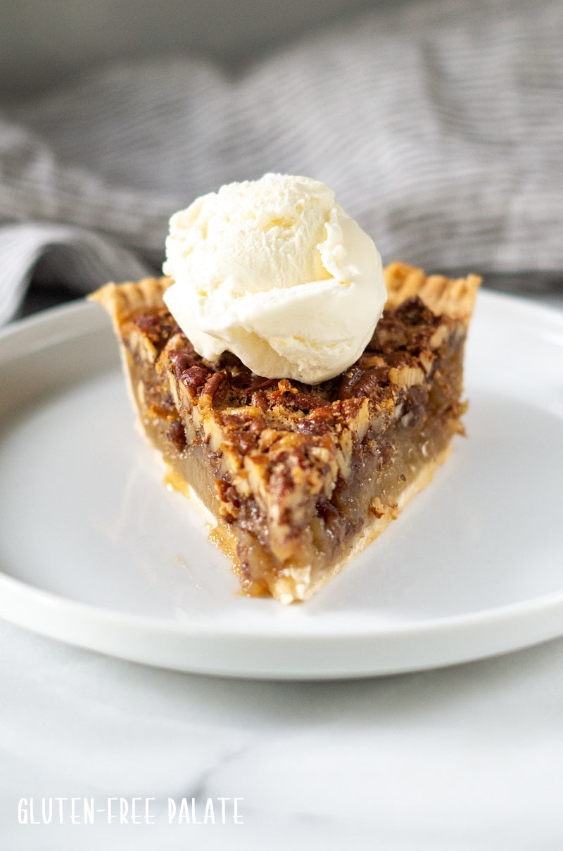 a slice of gluten-free pecan pie topped with a scoop of vanilla ice cream