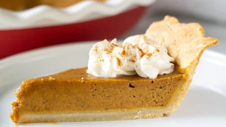 Side view of a slice of gluten free pumpkin pie with whipped cream on top