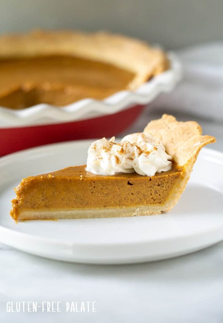 Side view of a slice of gluten free pumpkin pie with whipped cream on top