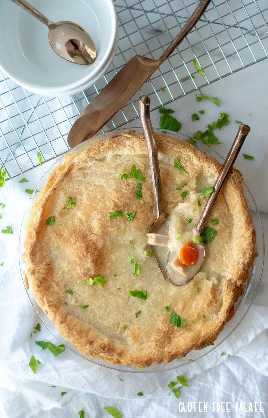 gluten free turkey pot in in a glass pie pan with two spoons dipped into the pie