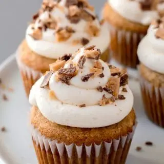 a close up of grain-free banana toffee cupcakes with white frosting and toffee on top