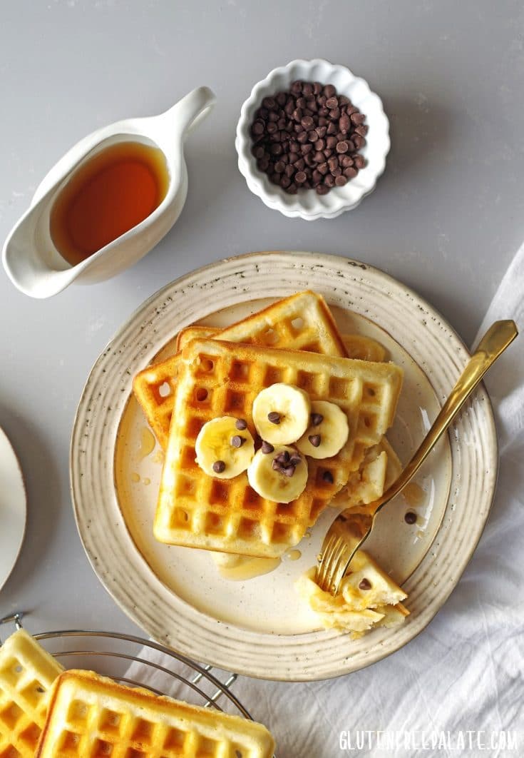 top view of Gluten-Free Waffles topped with bananas and mini chocolate chips on a plate with a fork