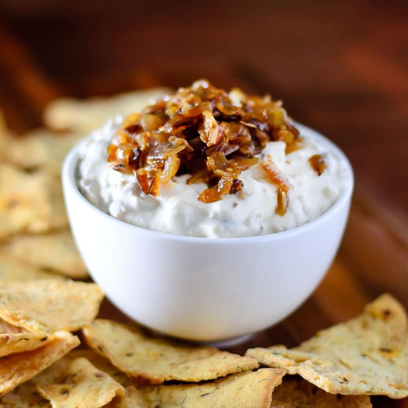 a white bowl filled with dip, topped with grilled onions