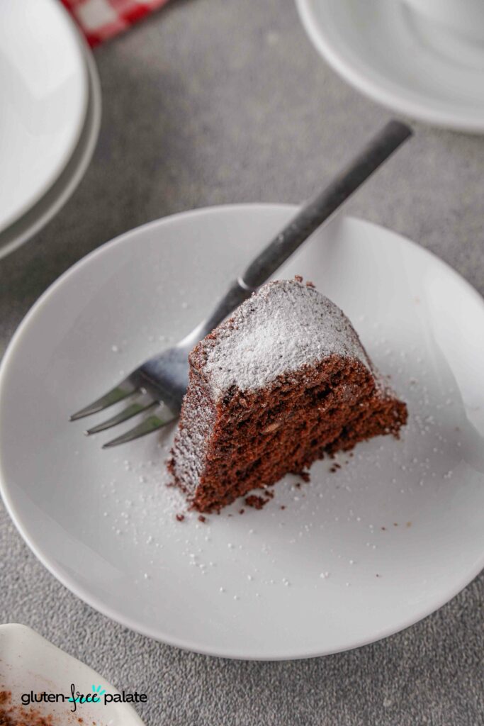 A slice of Gluten-free chocolate bundt cake on a white plate with a fork.