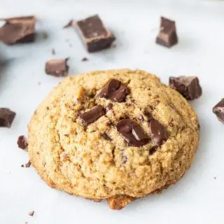 Paleo Chocolate Chip Cookie on a white background with chunks of chocolate around it