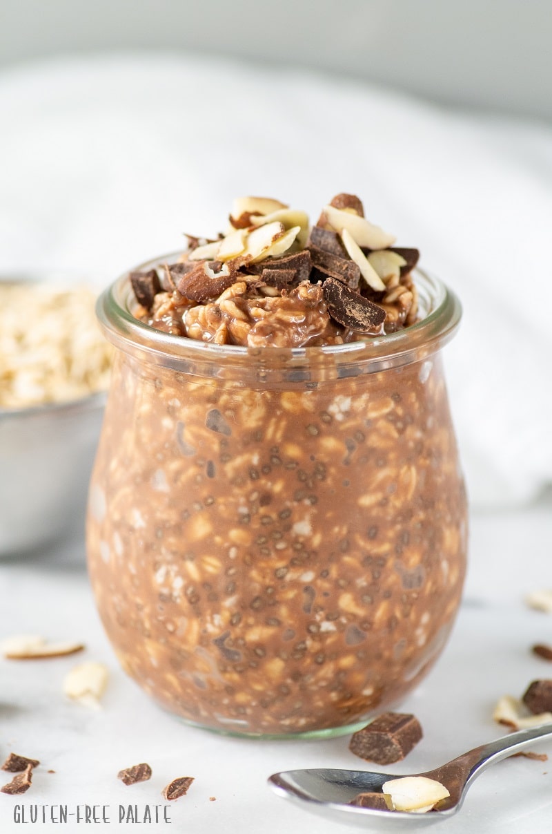 chocolate overnight oats in a glass jar topped with chocolate chunks and sliced almonds