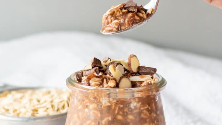 chocolate overnight oats in a glass jar with a spoon of oats