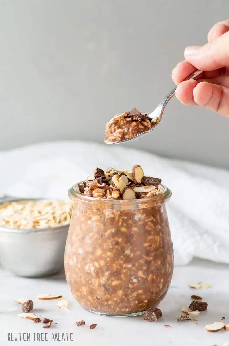 chocolate overnight oats in a glass jar with a spoon of oats
