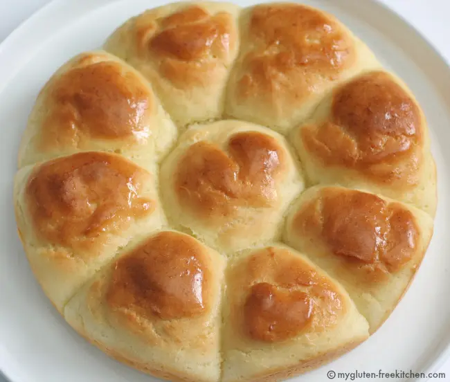 Nine Gluten Free Dinner Rolls on a white plate in a circle pattern