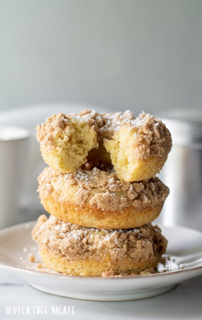 three gluten free crumb donuts stacked on a plate