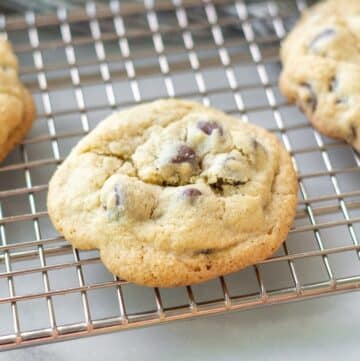 A side view of a gluten-free chocolate chip cookies on a wire cooling rack.