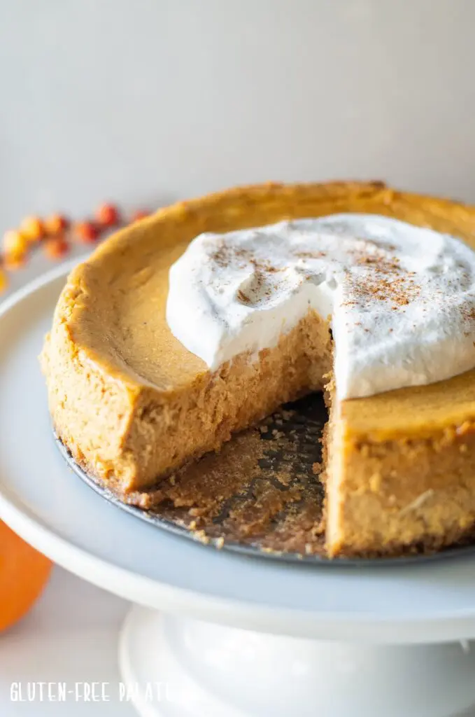 Gluten-Free Pumpkin Cheesecake on a white cake platter with a slice