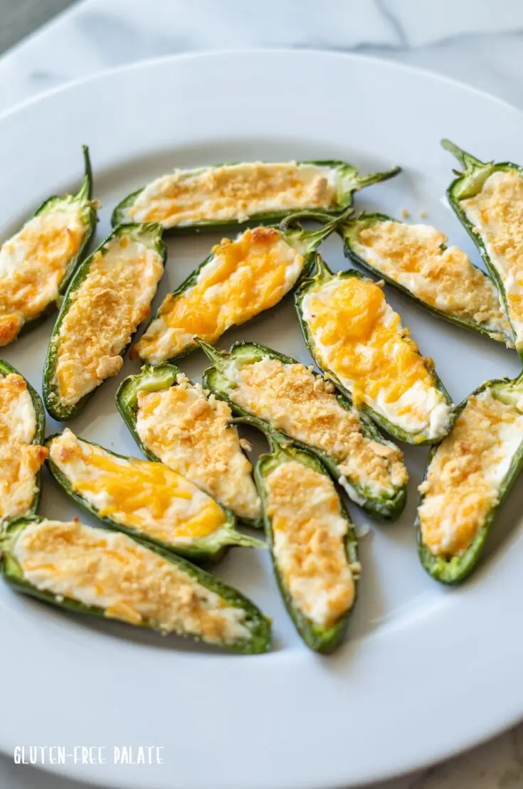 jalapeno poppers with melted cheese and cracker crumbs on top, on a white plate