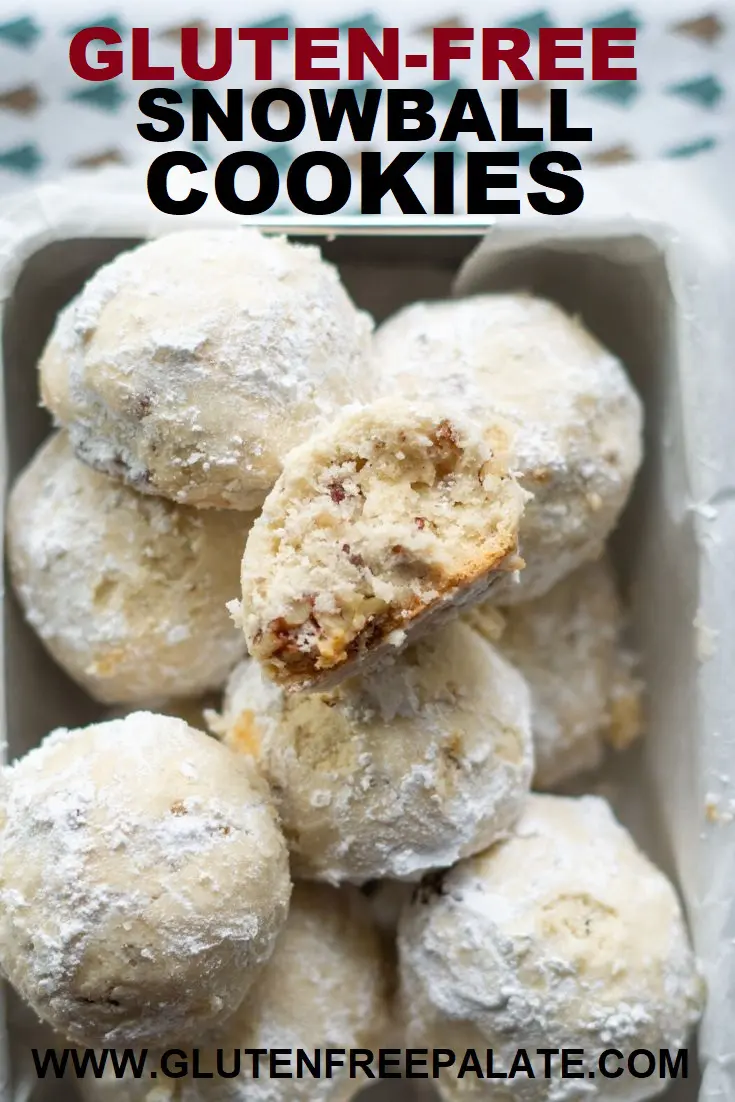 gluten free snow ball cookies in a square metal tin lined with wax paper, one cookie has a bite out with words at the top, gluten free snowball cookies