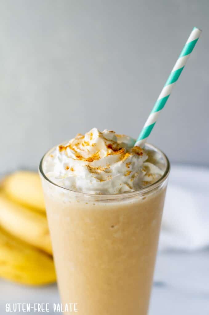 A turmeric Smoothie in a glass with a striped staw.