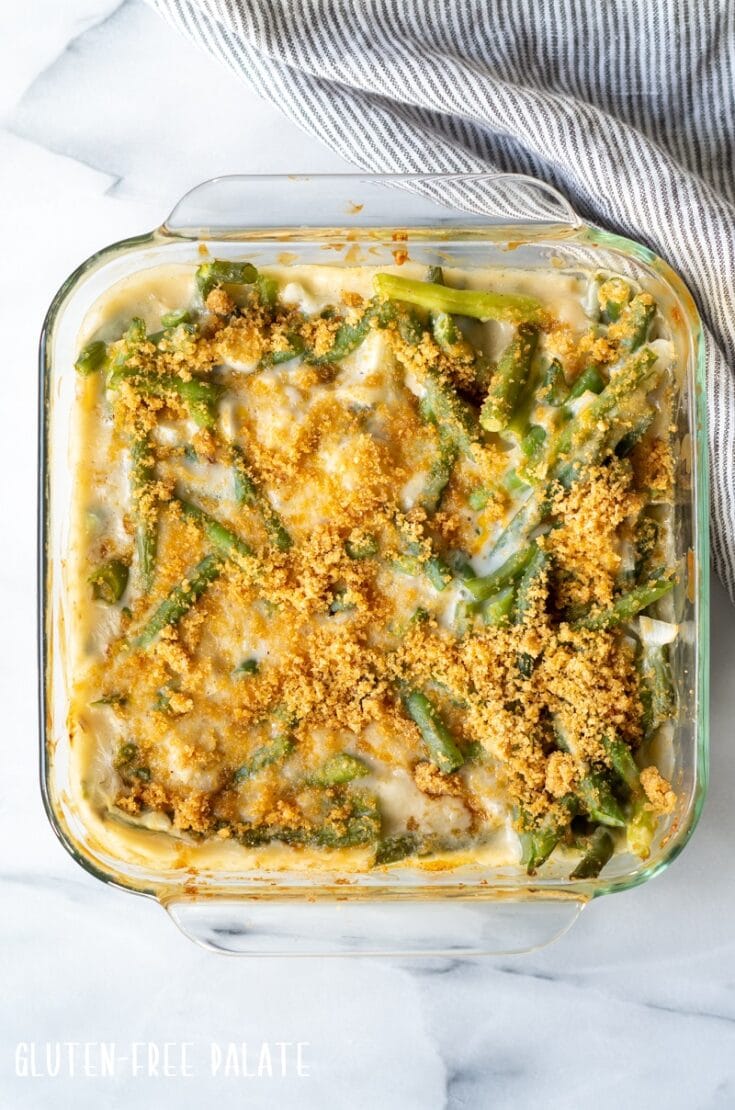 Gluten Free Green Bean Casserole in a glass baking dish with a stripe towel next to it