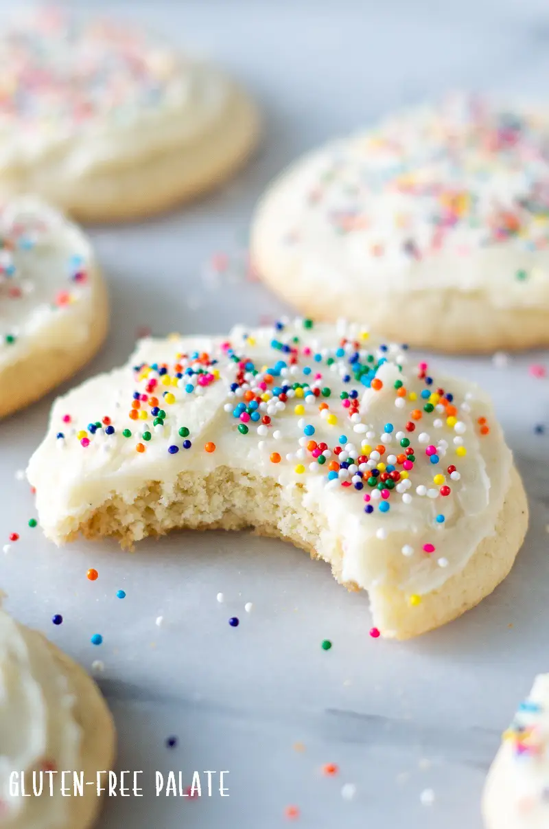 Gluten-Free Sugar Cookies with colored sprinkles on top with a bite out of one cookie